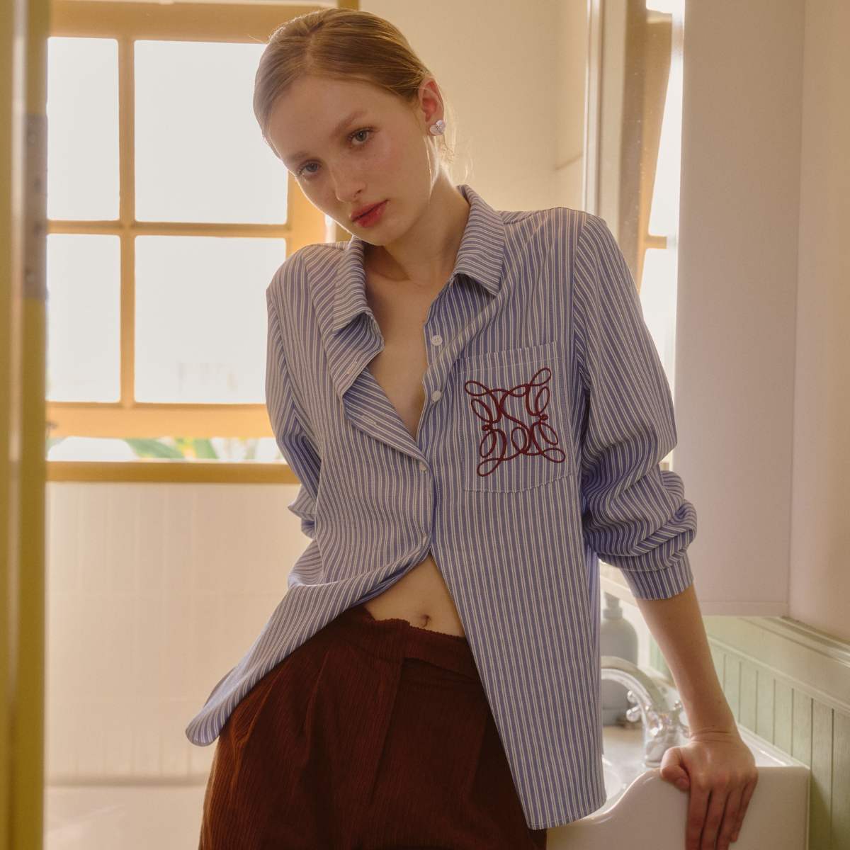 Closet Crush Urban Luxe - เสื้อเชิ้ตลายทางเเขนยาว เเต่งกระดุมหน้า ปักลายที่กระเป๋าเสื้อ สีฟ้า ราคา 509 บาท*ส่งฟรี